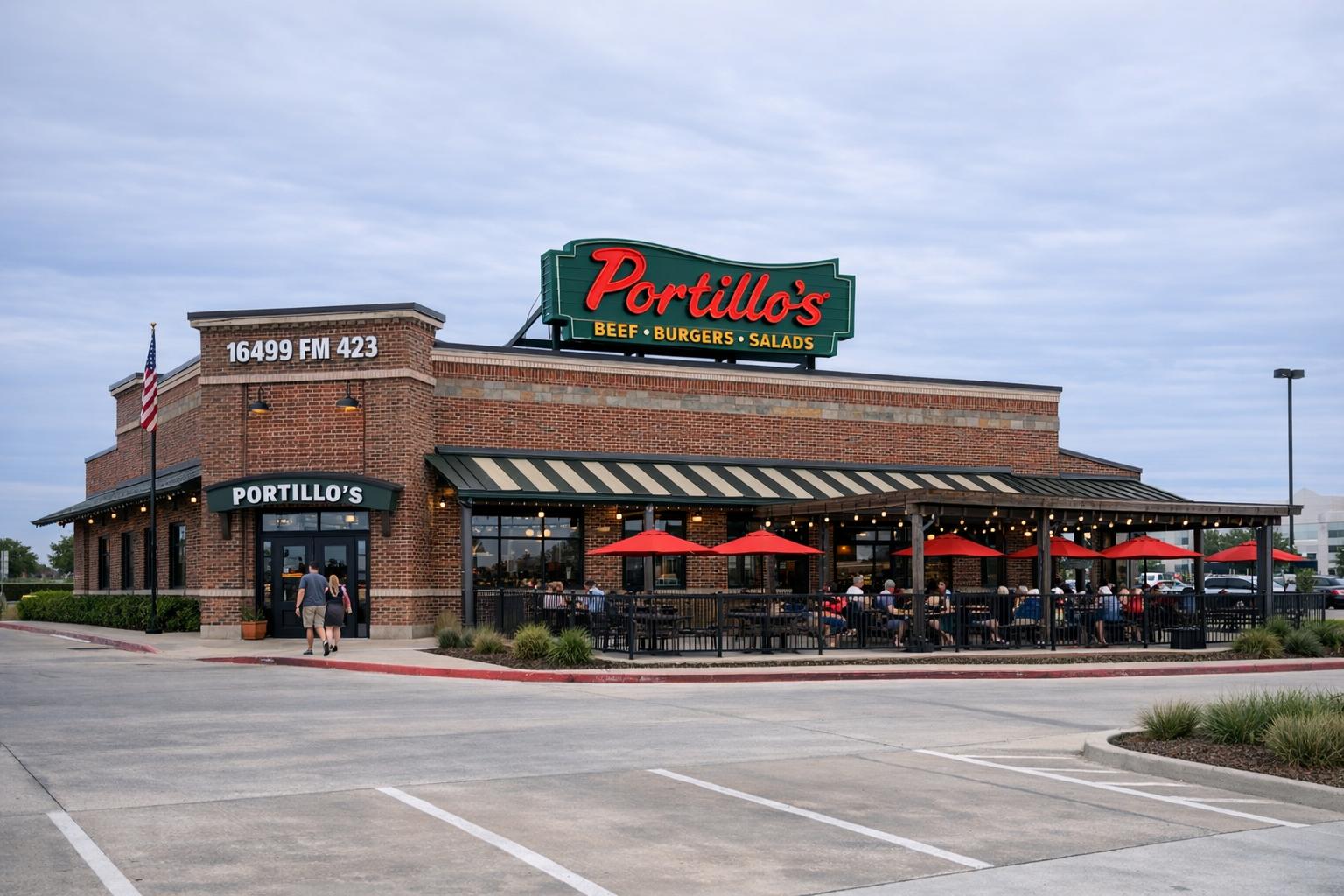 Exterior of a Portillo's restaurant with outdoor patio and signage at an urban-suburban site under overcast sky.